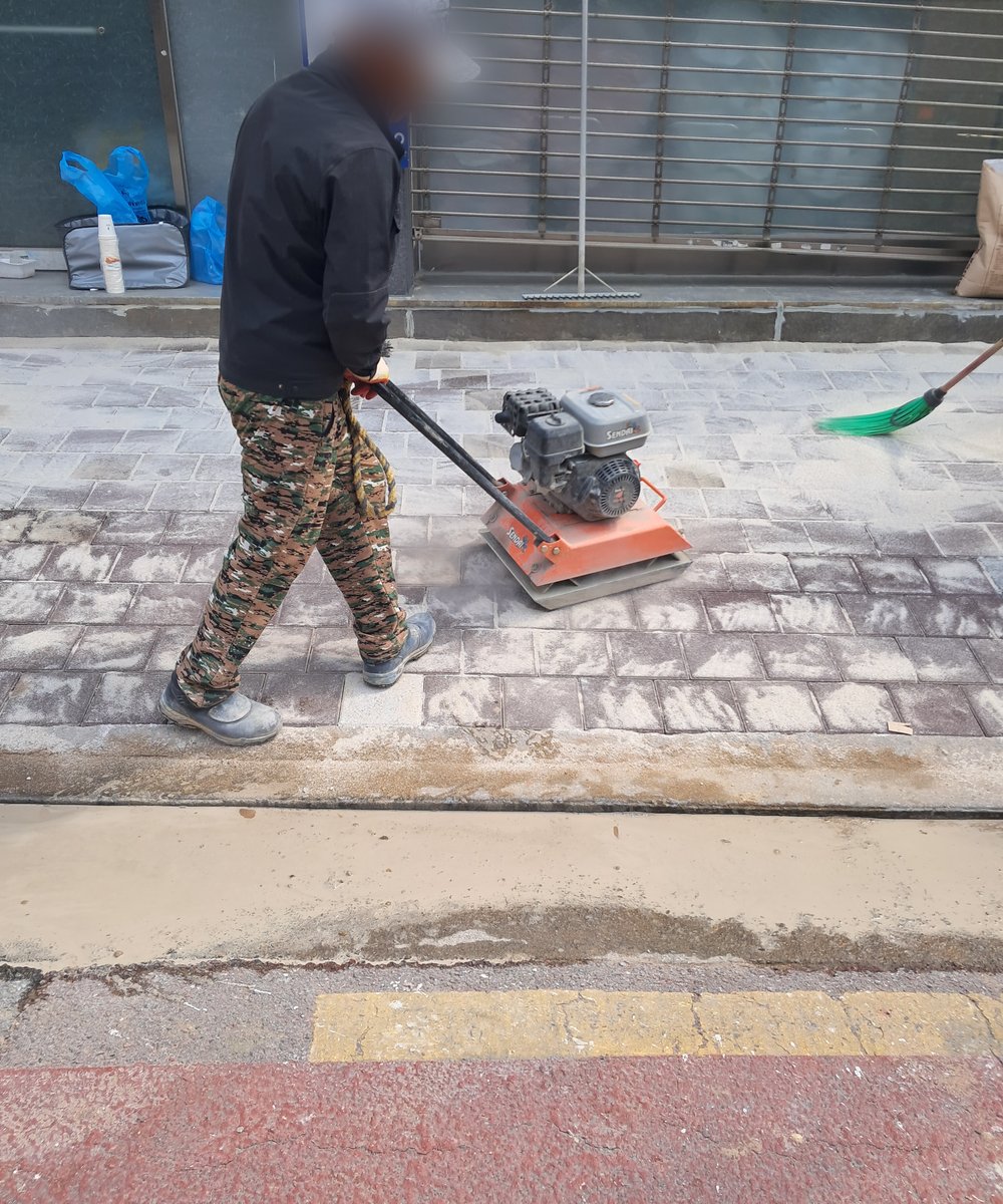 규사를 뿌리고 새 보도블럭 바닥을 다지는 작업